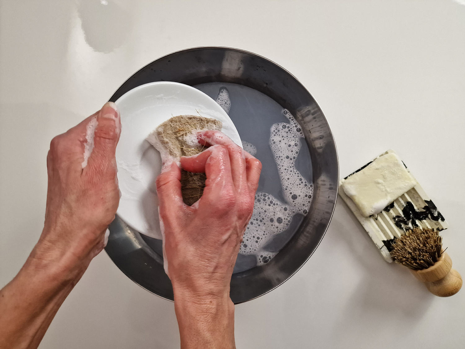 Vierka lava i piatti utilizzando un sapone solido per i piatti che ha realizzato lei stessa con materie prime di Handymade.