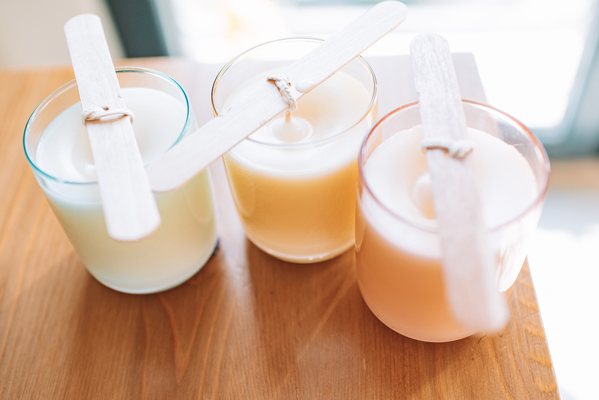 Candele create con le cere Handymade. Tre contenitori di vetro con cera liquida trasparente, appena colata.